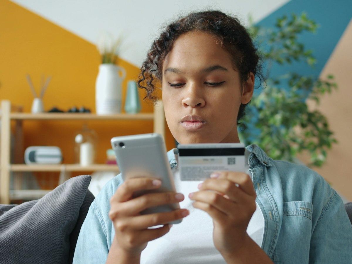 Woman paying for an online order with her phone and bank card