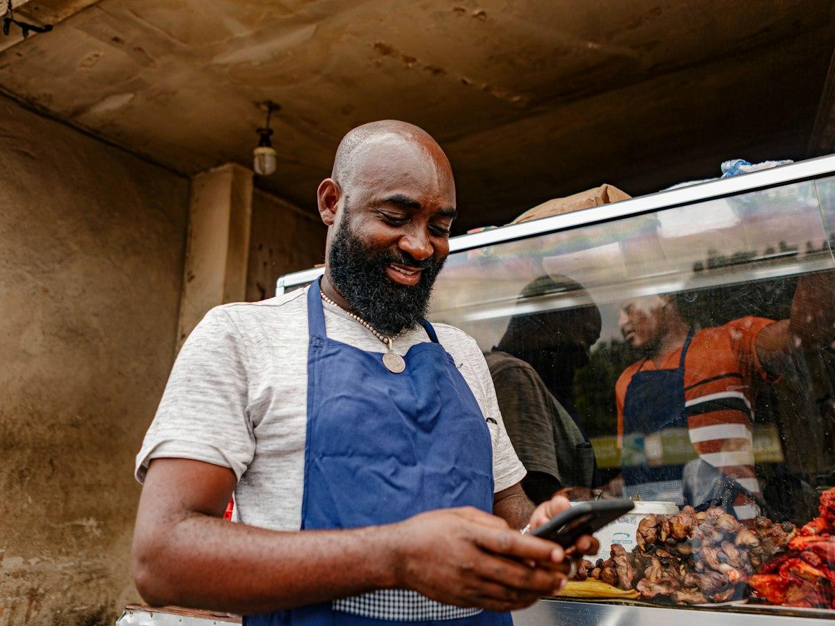 Shop owner in an apron checking orders on his phone
